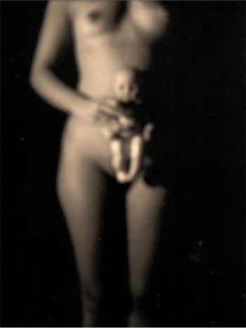 Blurry nude female torso holding a doll in front of her body